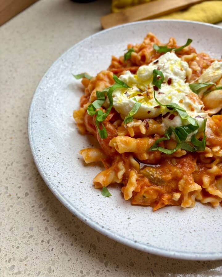 plate of 20 minute cherry tomato burrata pasta with fresh basil, burrata, and crushed red pepper flakes