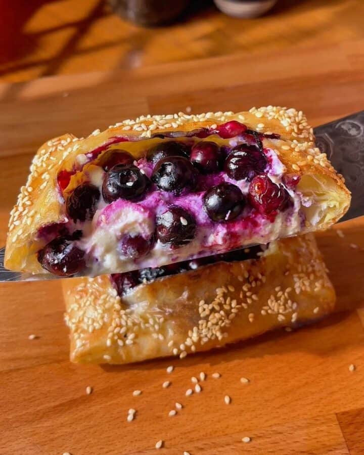 slice of blueberry ricotta rice paper danish with ricotta center and jammy blueberry and sesame seed topping