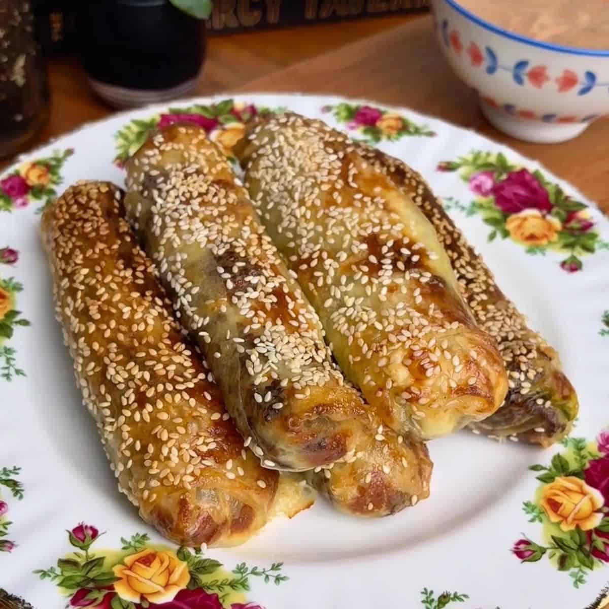 stack of cheeseburger rice paper spring rolls topped with sesame seeds
