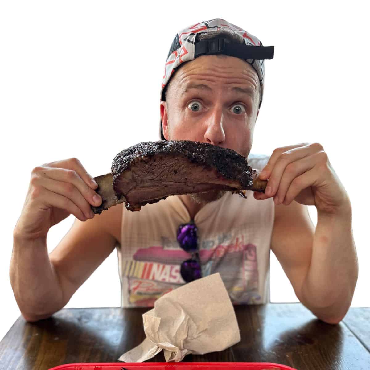 Chef Josh sitting at a table eating a beef rib