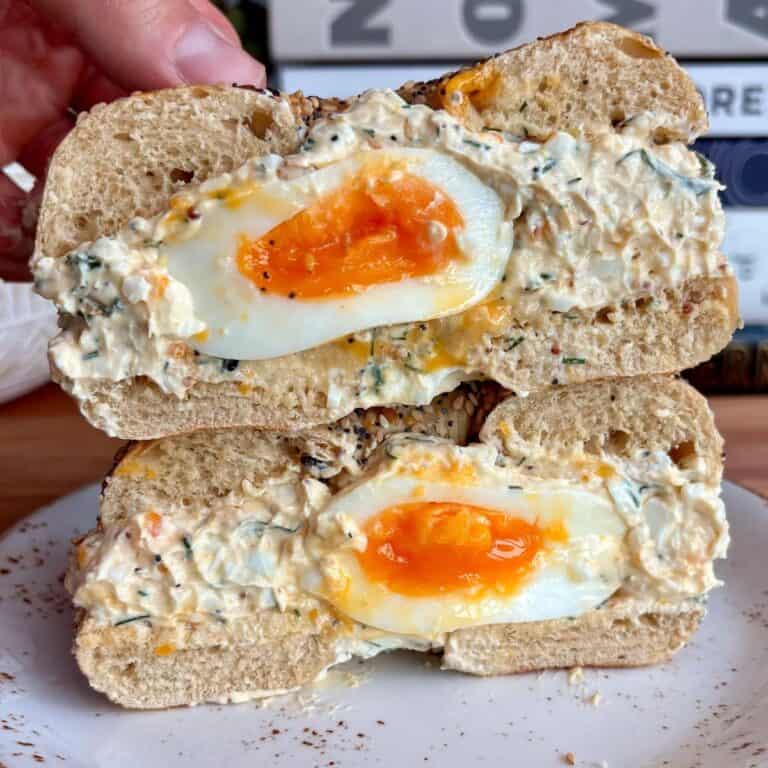 chopped egg salad everything bagel with a soft boiled egg in the middle