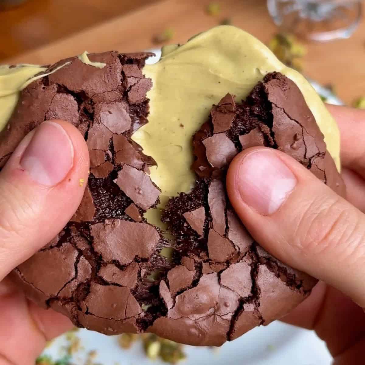 crispy crackly chewy pistachio brownie cookie with pistachio butter in the middle