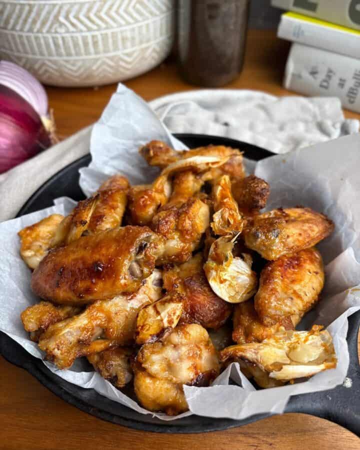 bowl of crispy maple garlic chicken wings and roasted garlic cloves