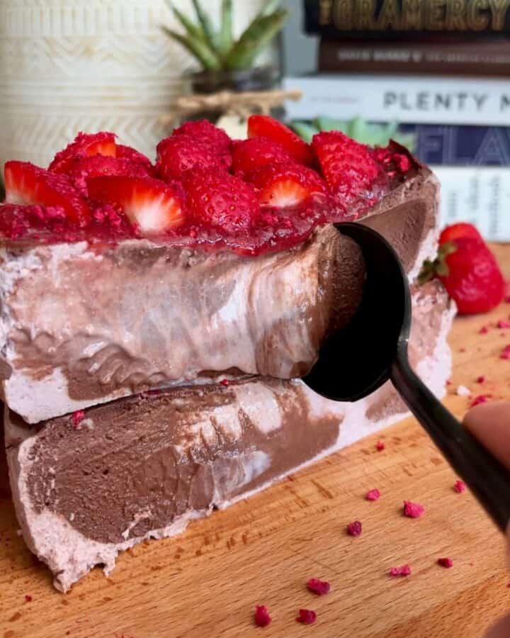 fudgy high protein dark chocolate strawberry cheesecake topped with strawberry jam, fresh strawberries and freeze-dried strawberry crumble