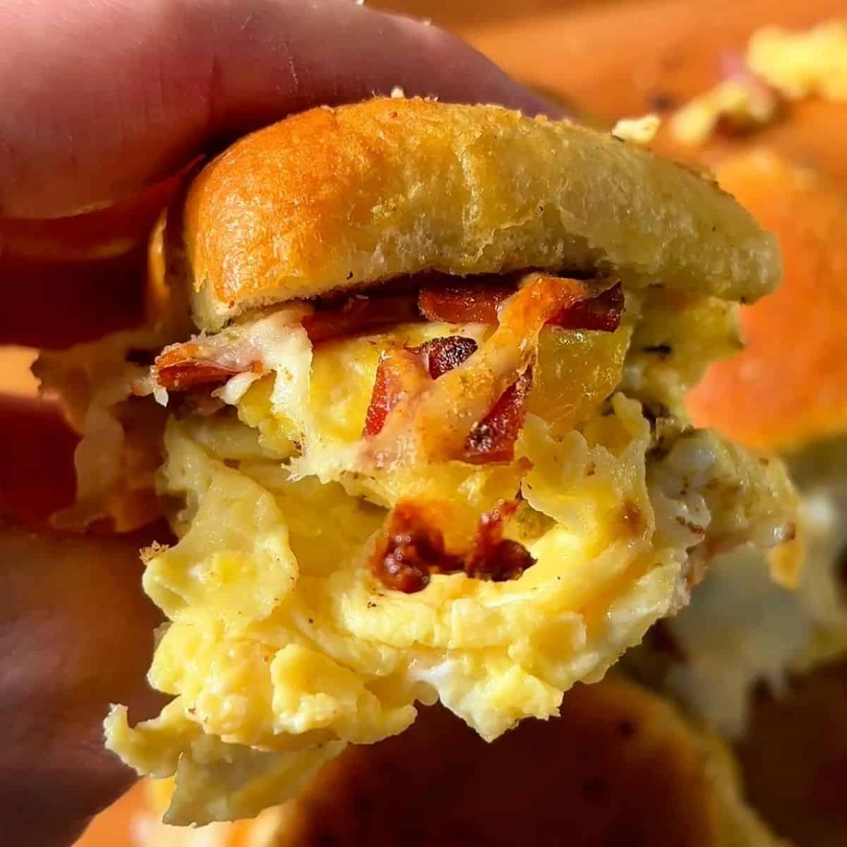 garlic and herb bacon egg and cheese slider on a soft Hawaiian roll with crispy bacon and fluffy eggs