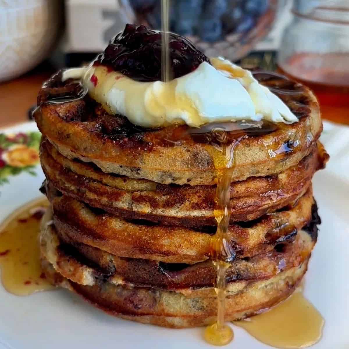 stack of healthy blueberry mini waffles topped with yogurt, fresh blueberries and maple syrup drizzle