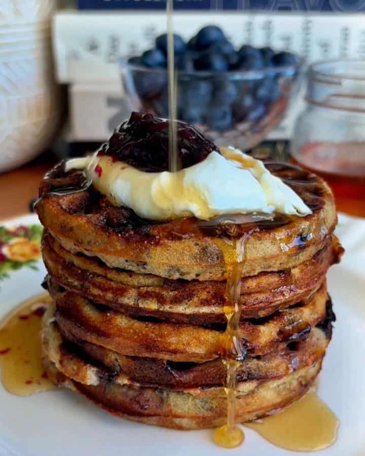 stack of healthy blueberry mini waffles with dollop of yogurt and blueberry jam and drizzled with maple syrup