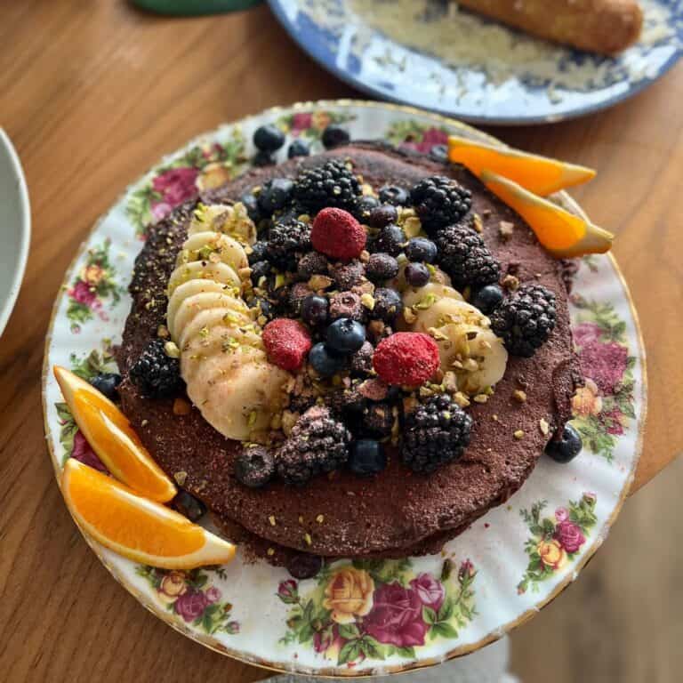 Healthy chocolate protein pancakes with fresh berries, chopped pistachios and orange slices