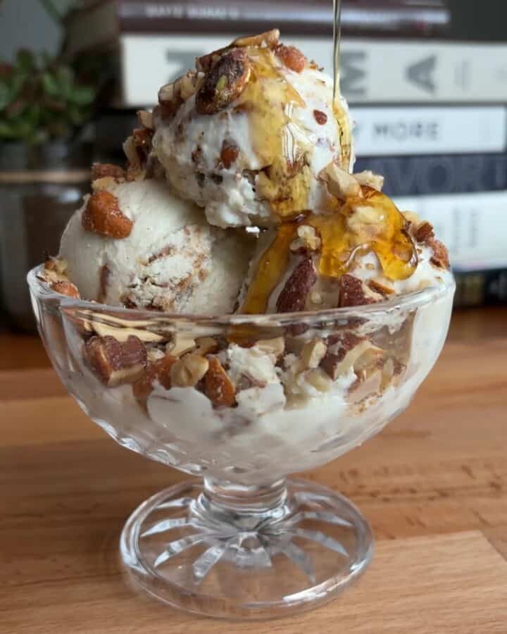high protein peanut butter praline ice cream sundae with chopped nuts and maple syrup drizzle