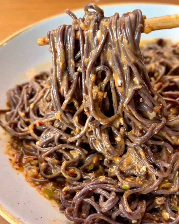 bowl of spicy sesame chili noodles in sesame chili sauce, topped with sesame seeds