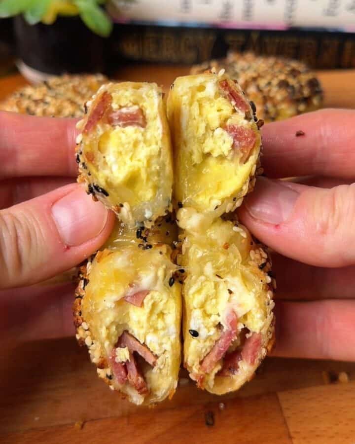 a bacon, egg, and cheese rice paper bagel cut in half showing melty cheese, crispy bacon and egg inside