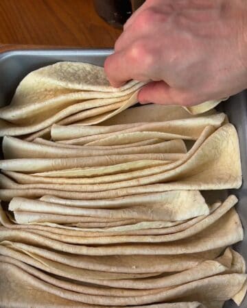a baking dish filled with folded tortillas as part of making cheesy garlic and herb tortilla pull apart bread