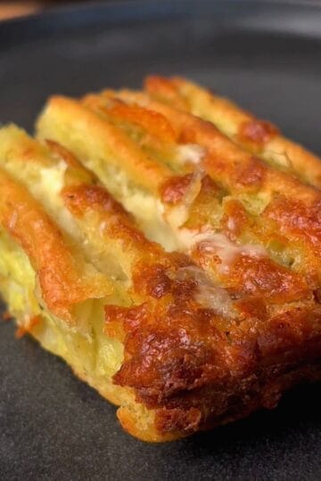 a crispy piece of cheesy garlic & herb tortilla pull apart bread on plate
