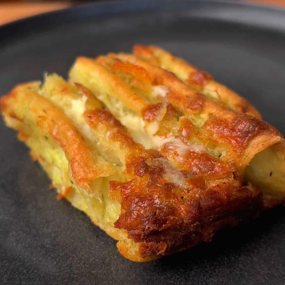 a crispy piece of cheesy garlic & herb tortilla pull apart bread on plate