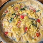 creamy one pan tomato and spinach fettuccine in a pan, sprinkled with black pepper