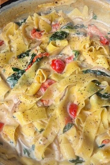 creamy one pan tomato and spinach fettuccine in a pan, sprinkled with black pepper
