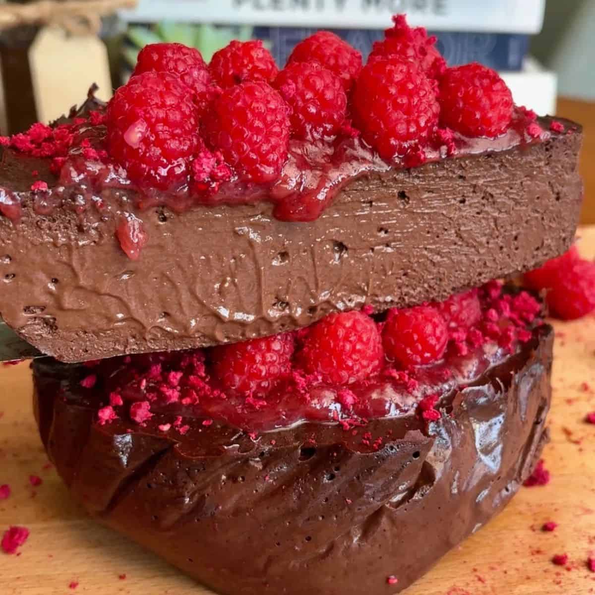 slice of fudgy, high protein dark chocolate raspberry cheesecake topped with fresh raspberries and freeze dried raspberries