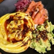high protein smoked salmon breakfast bowl made with soft scrambled eggs, smoked salmon, pickled red onions, avocado and sesame sauce