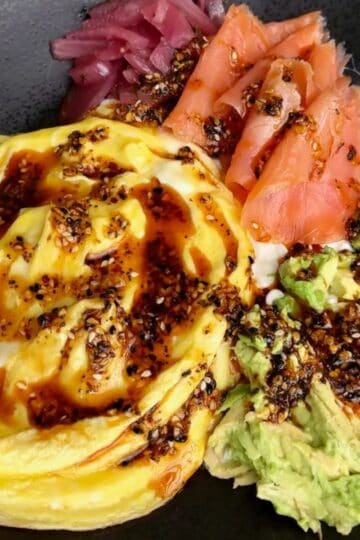 high protein smoked salmon breakfast bowl made with soft scrambled eggs, smoked salmon, pickled red onions, avocado and sesame sauce
