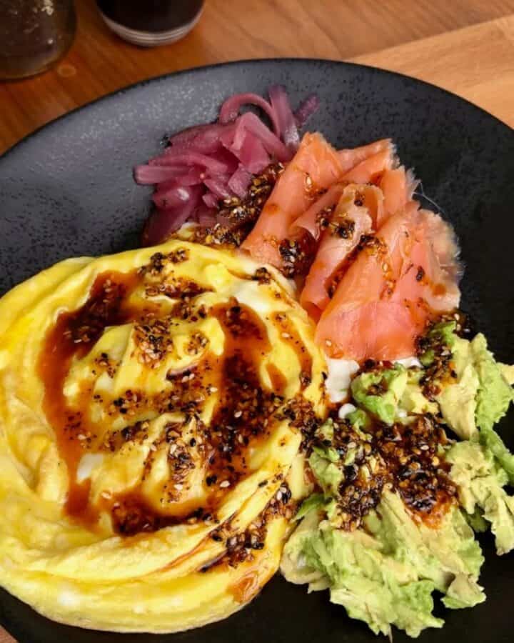 high protein smoked salmon breakfast bowl with soft scrambled eggs, avocado, pickled onions and a soy drizzle