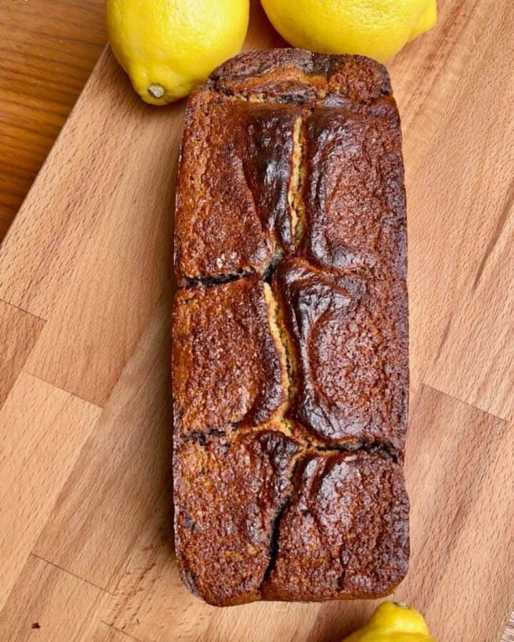 golden brown lemon blueberry marble loaf on a cutting board with lemons