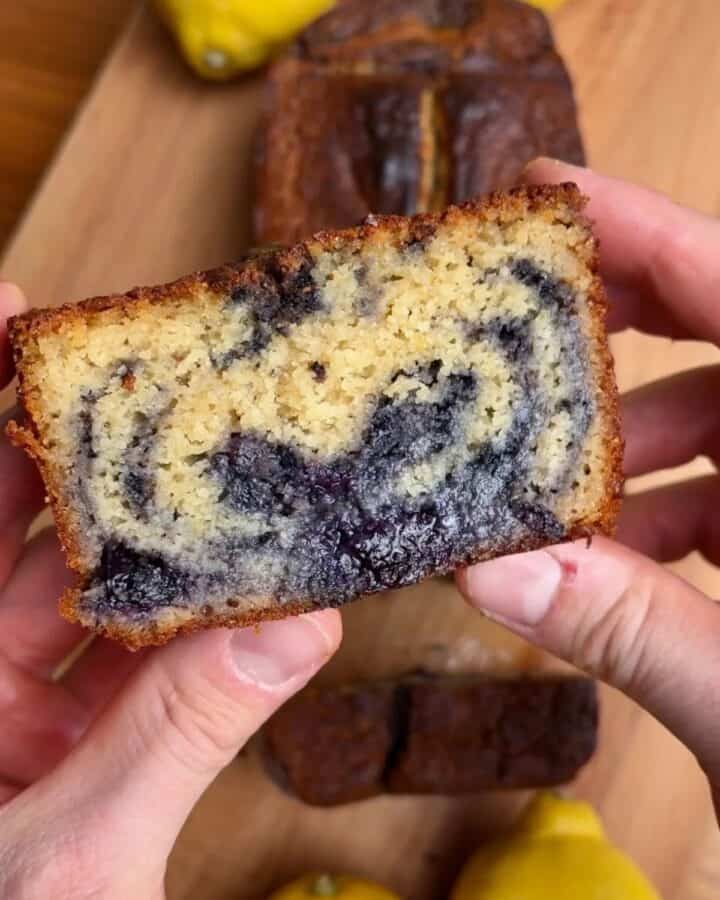 slice of golden brown lemon blueberry marble loaf with moist cakey inside and colorful blueberry swirl