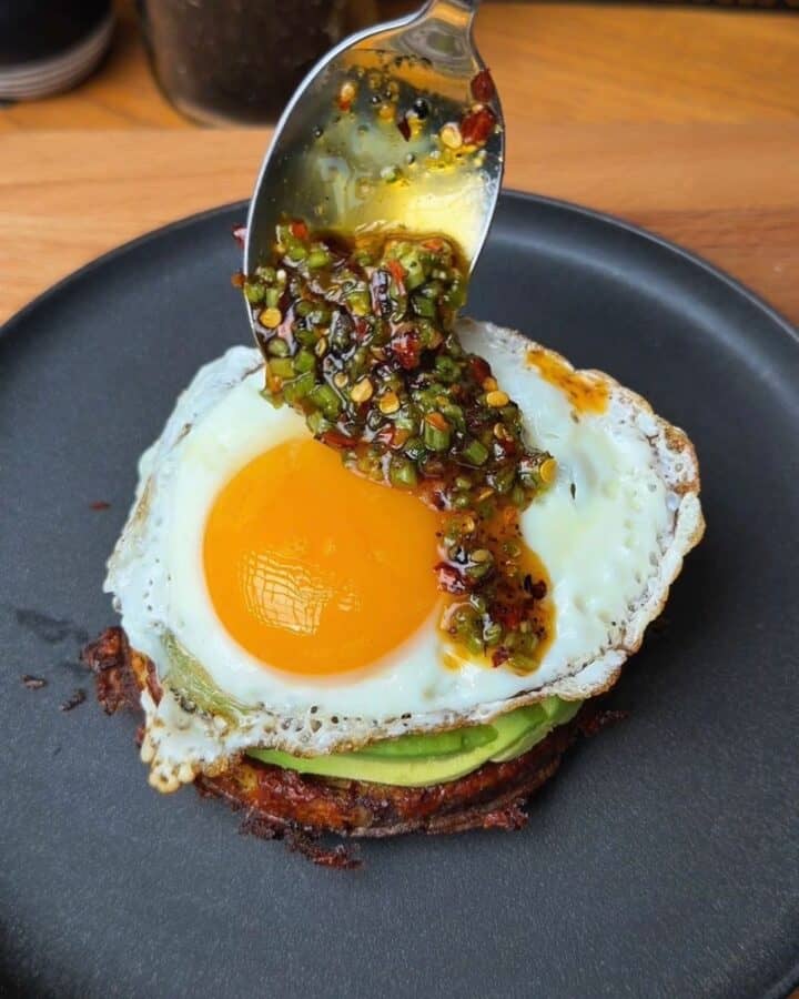 potato waffle breakfast stack being topped with herby drizzle