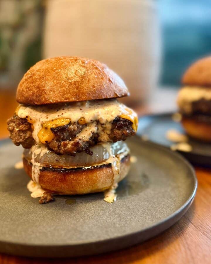 thick, juicy burger sitting atop a crispy caramelized onion, sandwiched between two toasted buns and drenched in punchy burger sauce