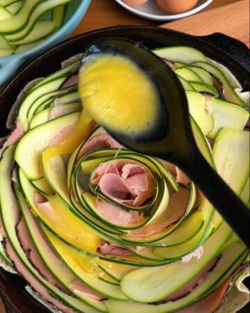 assembly of crispy zucchini and ham tortilla quiche, pouring egg yolk into the zucchini and ham layers