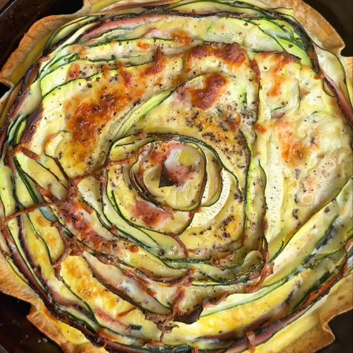 freshly baked crispy zucchini and ham tortilla quiche with golden brown edges and melty cheese