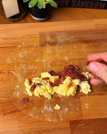 egg and bacon on a a rice paper sheet in prep for bacon egg and cheese rice paper bagel