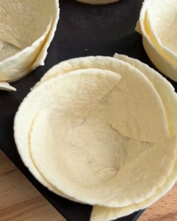 a tortilla in a muffin tin in prep for the making of a bacon, egg, and cheese tortilla muffin