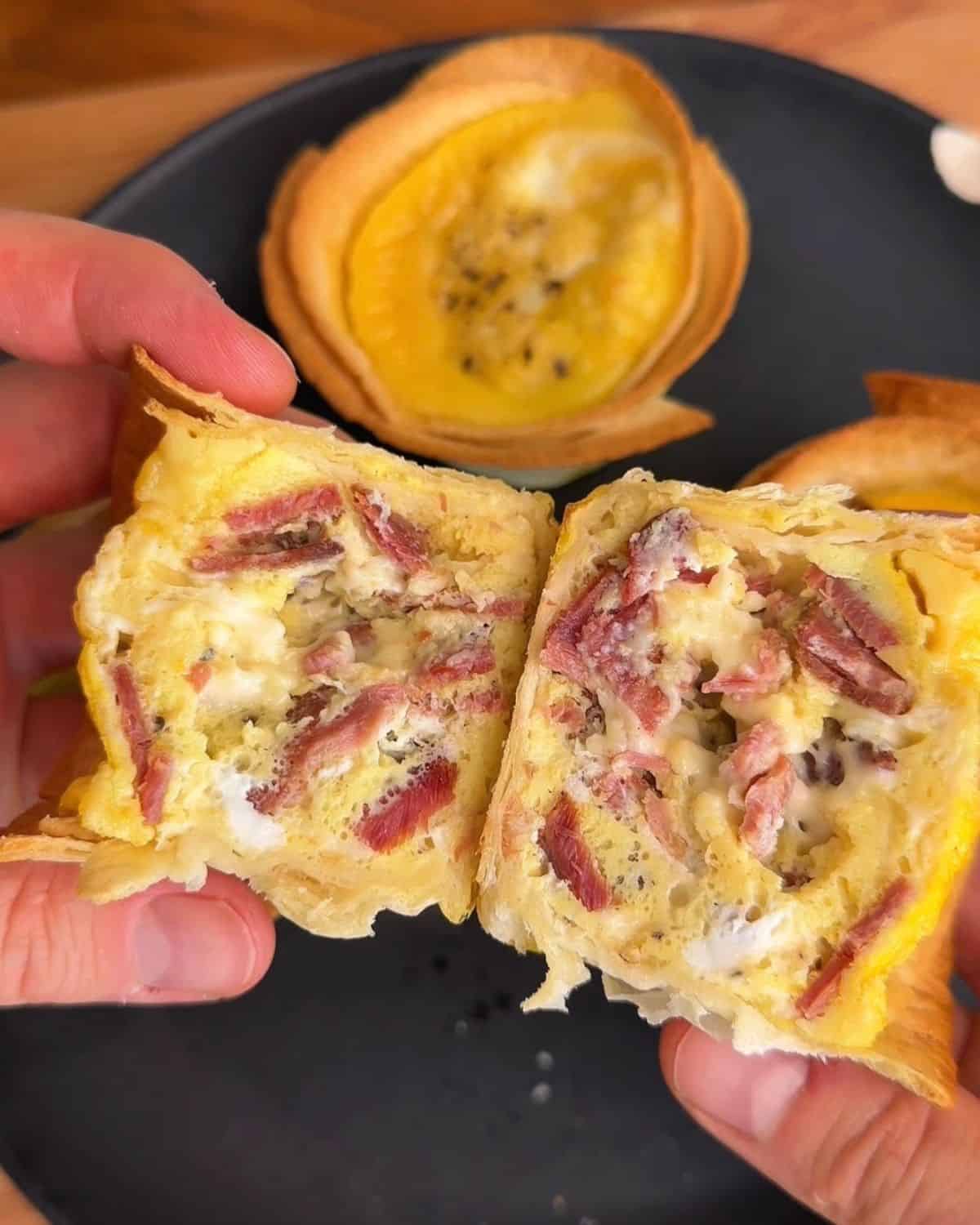 a bacon, egg and cheese tortilla muffin sliced in half, showing the melty cheese, bacon and scrambled egg center