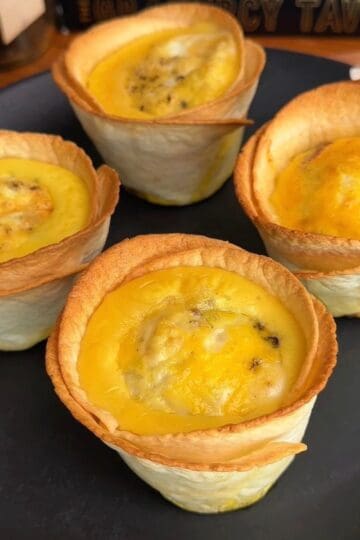 a plate of freshly baked bacon, egg and cheese tortilla muffins with crispy, golden brown edges and eggy centers