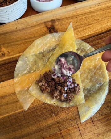 red onion and ground beef on top of cut rice paper sheets for the making of a big mac rice paper croissant