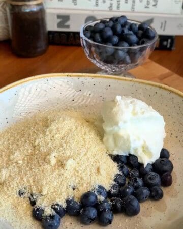 almond flour, greek yogurt, and blueberries in a bowl in prep for the making of healthy baked blueberry donut holes