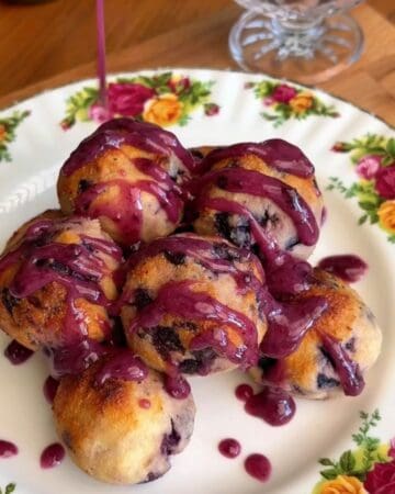 plate of healthy baked blueberry donut holes drizzled in blueberry glaze