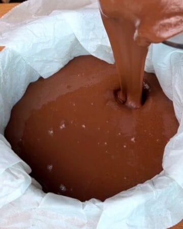 chocolate cheesecake batter being added to a round baking dish to go in the oven to bake