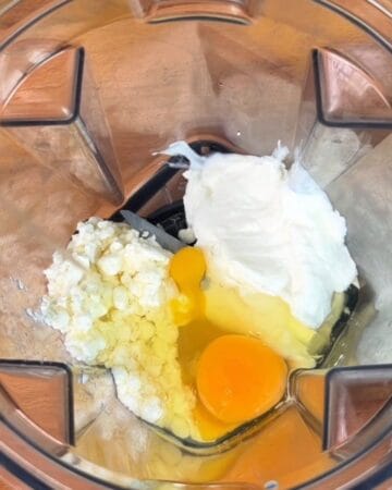 eggs, cottage cheese, honey, greek yogurt being added to a blender for cheesecake base