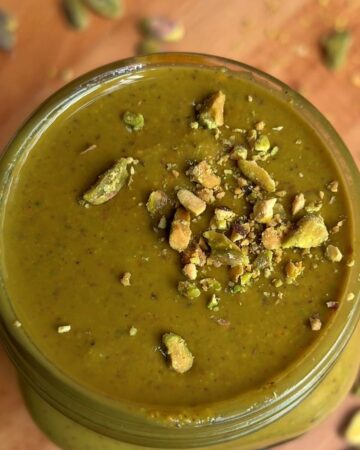 a finished jar of homemade pistachio butter with crushed pistachios on top