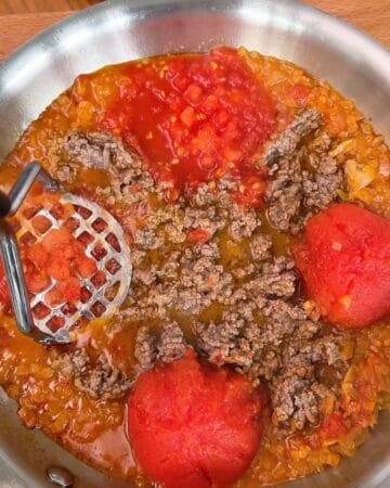 Homemade sauce featuring ground beef, tomatoes, and spices in a skillet.