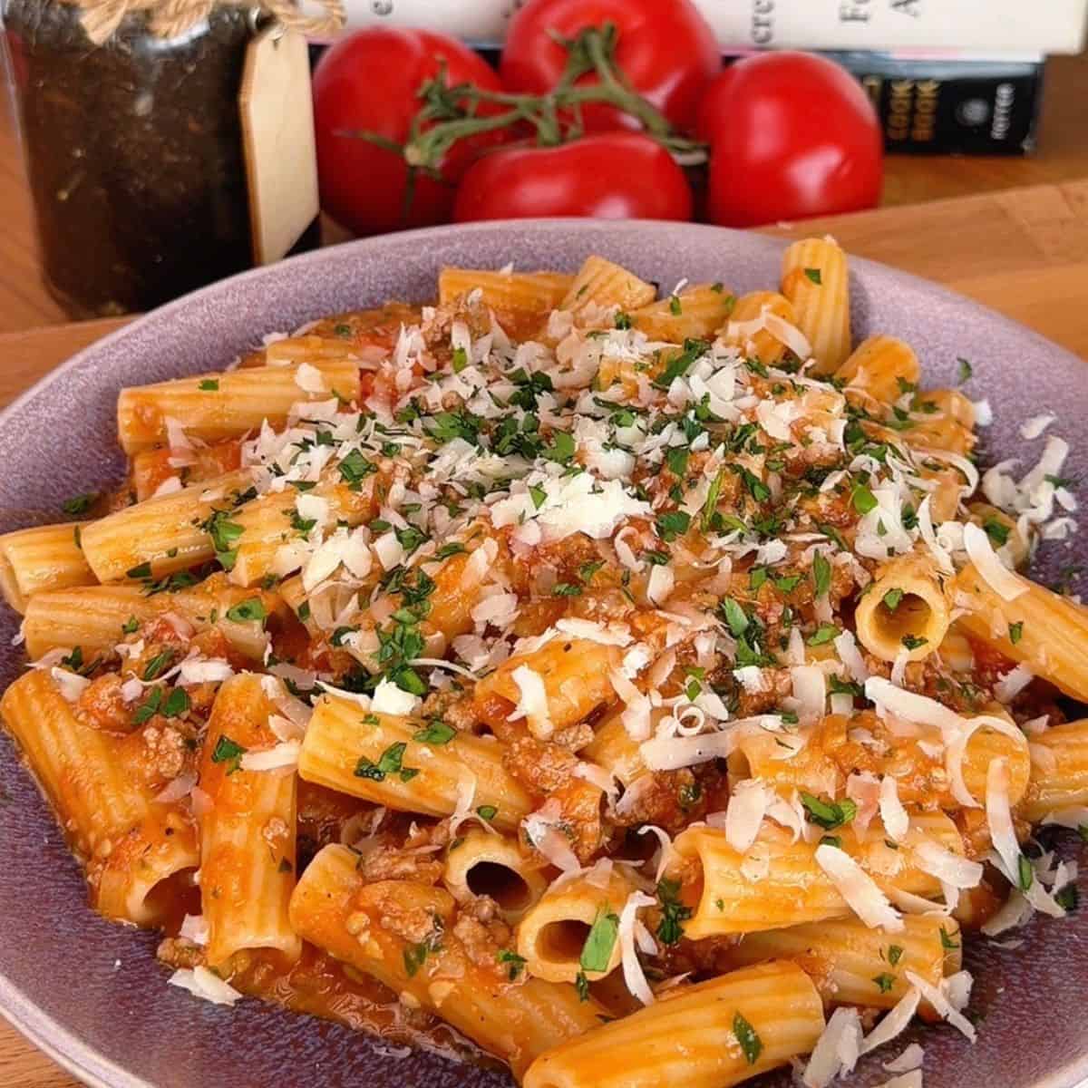a bowl of one-pan cheesy tomato beef rigatoni with shredded parmesan and parsley on top