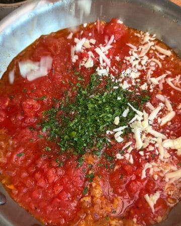 tomatoes, parsley, shredded cheese in a frying pan, simmering for one pan creamy tomato pasta