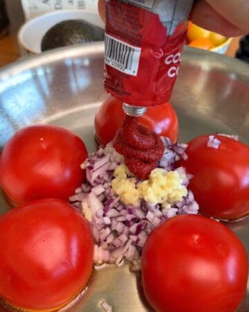 tomatos, onion, garlic and tomato paste in a frying pan being prepped for one pan creamy tomato pasta