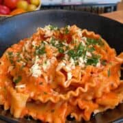 one pan creamy tomato pasta in a bowl, topped with parsley and cheese
