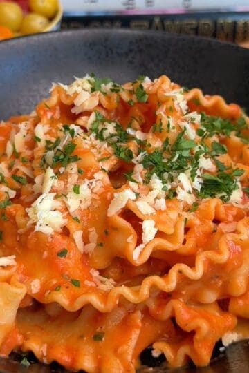 one pan creamy tomato pasta in a bowl, topped with parsley and cheese