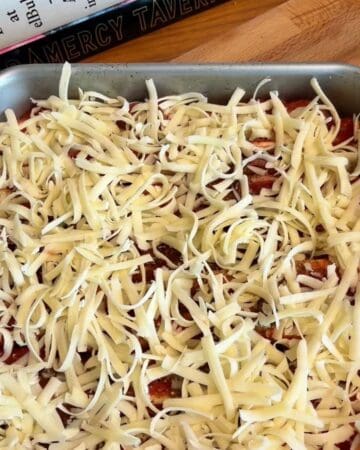 shredded cheese layered on top of tomato sauce and tortillas in prep for a batch of tortilla pull apart pizza bread