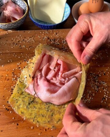 the assembly of a crispy rice paper croque madam with rice paper, everything bagel seasoning, and black forest ham