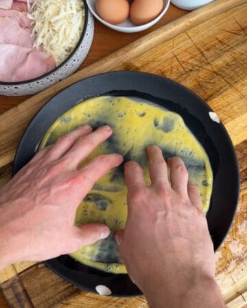 rice paper being dipped in egg yolk, in prep for the making of a crispy cuban rice paper sandwich