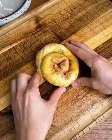 a cuban rice paper sandwich being rolled on a cutting board, preparing to go in the oven